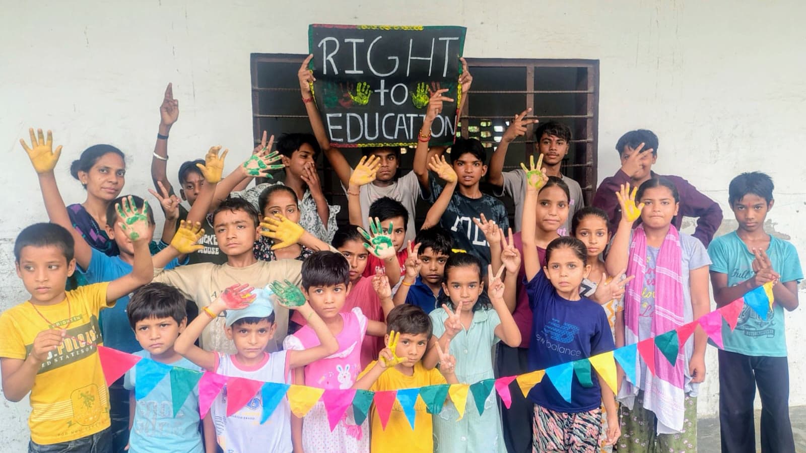 Children raising painted hands beneath a hand-lettered 'Right to Education' board